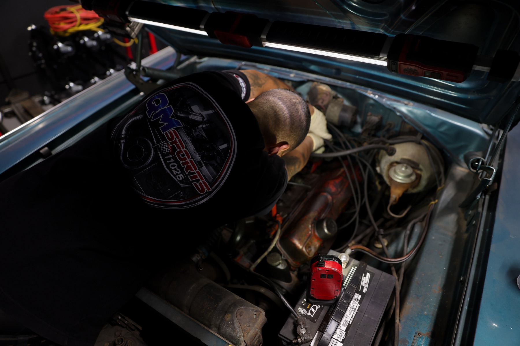 Overhead view of a technician working inside a classic engine bay