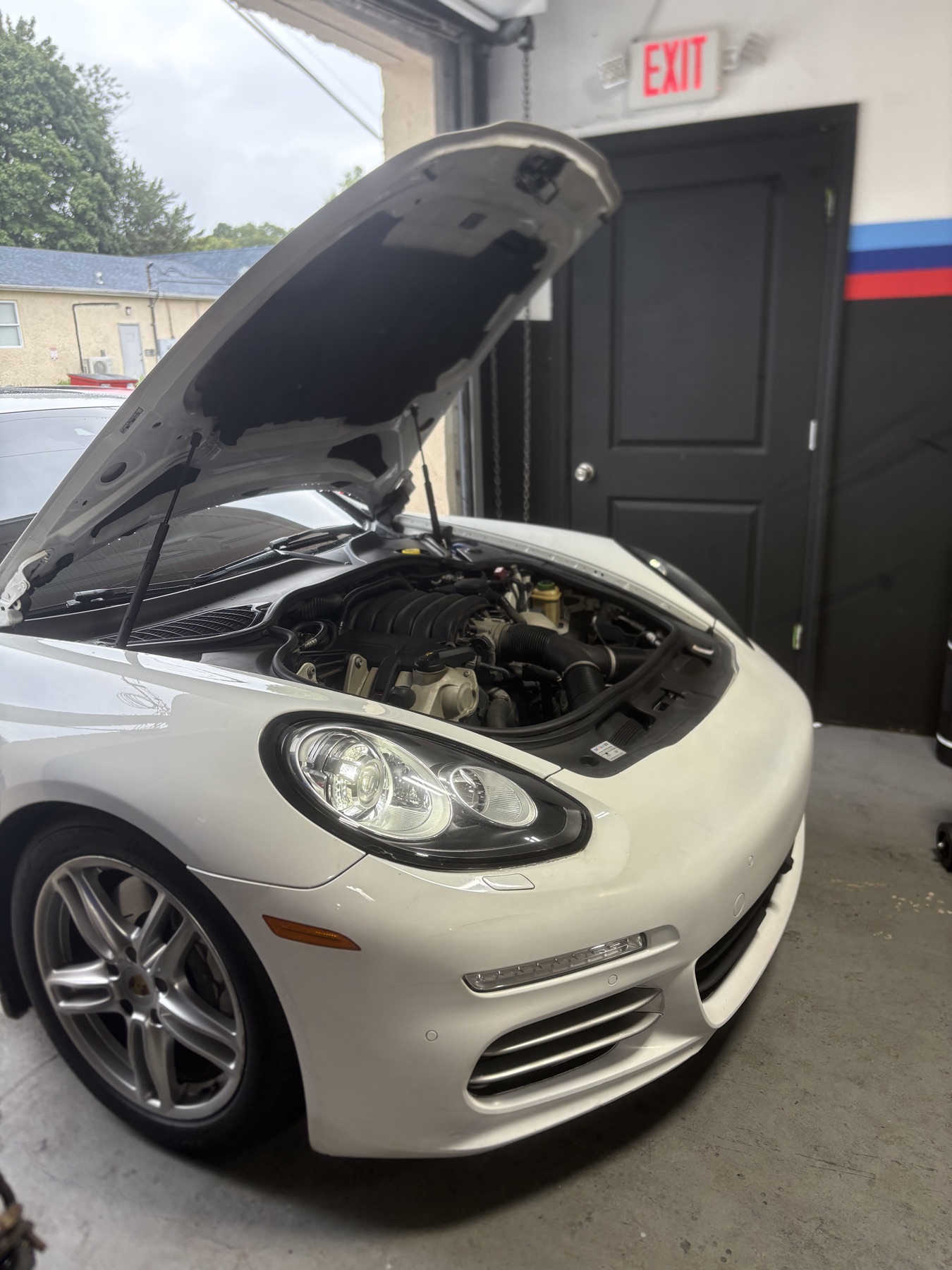 White Porsche Panamera with its hood open for service