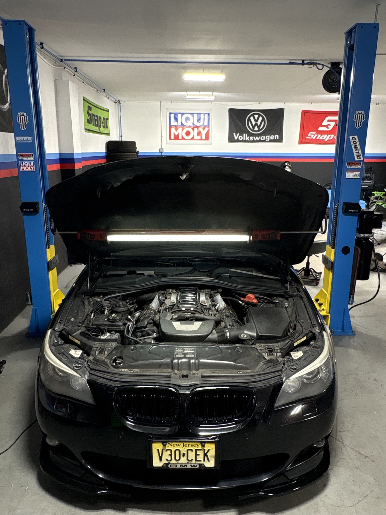 Black BMW positioned between service lifts with its hood open