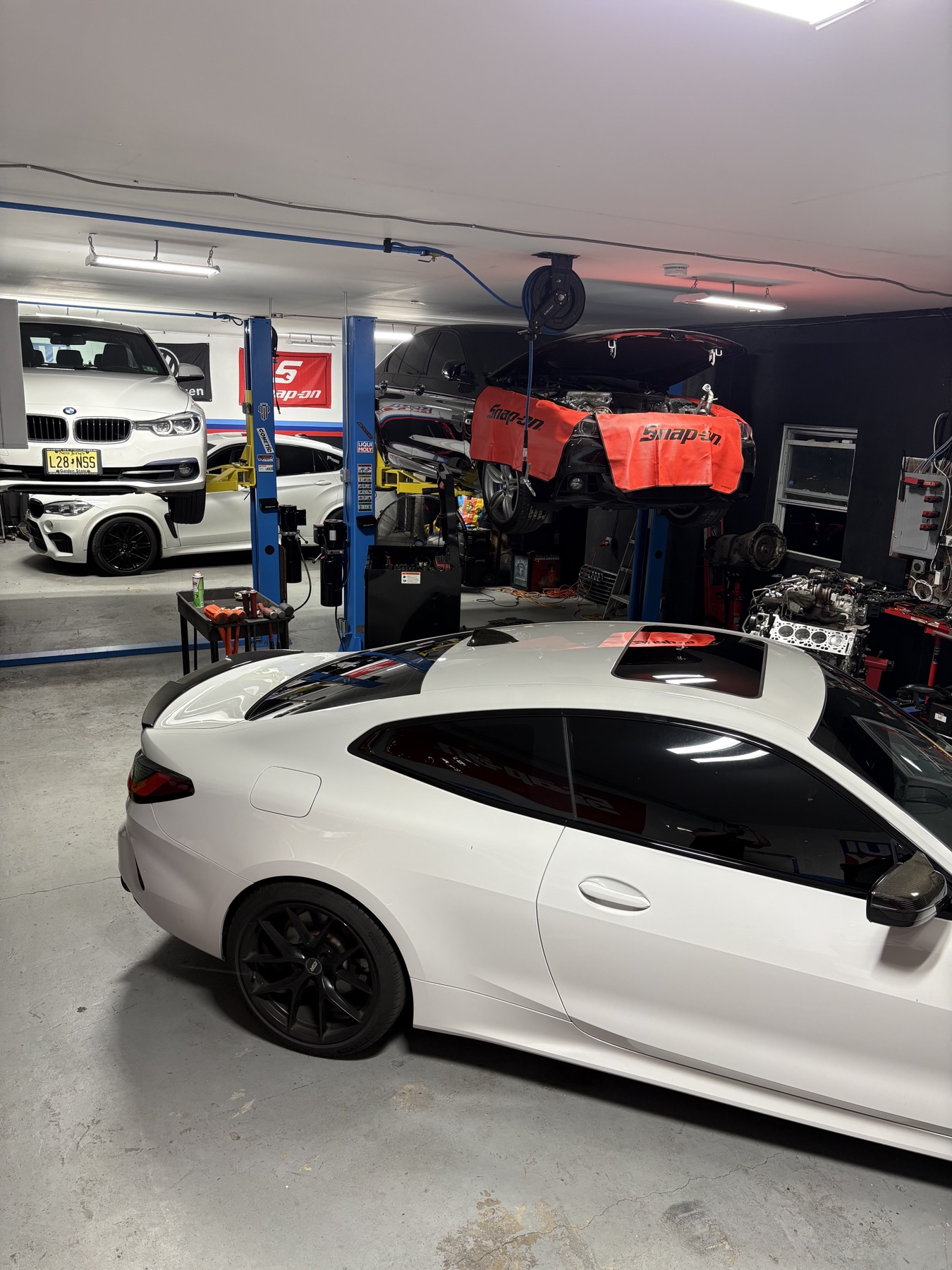 White performance coupe with several vehicles raised in service bays
