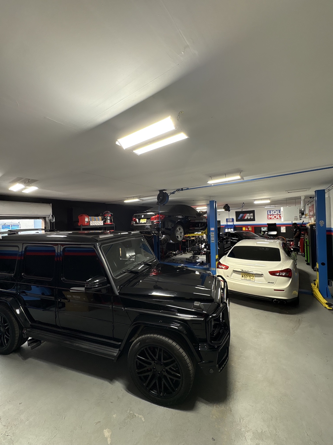 Black G-Wagon, Maserati, and BMWs inside the active workshop